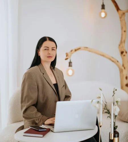 A confident businesswoman working on a laptop in a stylish modern home office, blending professionalism and comfort.